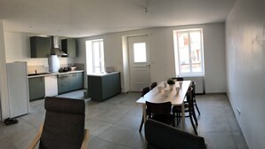 A modern kitchen with grey cabinets, a built-in oven, and a dining area with a table and chairs. - Charming house (Saint-Nectaire)