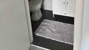 Et badeværelse med toilet, vask og hylder med toiletartikler.