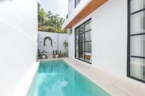 Une maison moderne dotée d’une piscine, de grandes fenêtres et de plantes en pot.