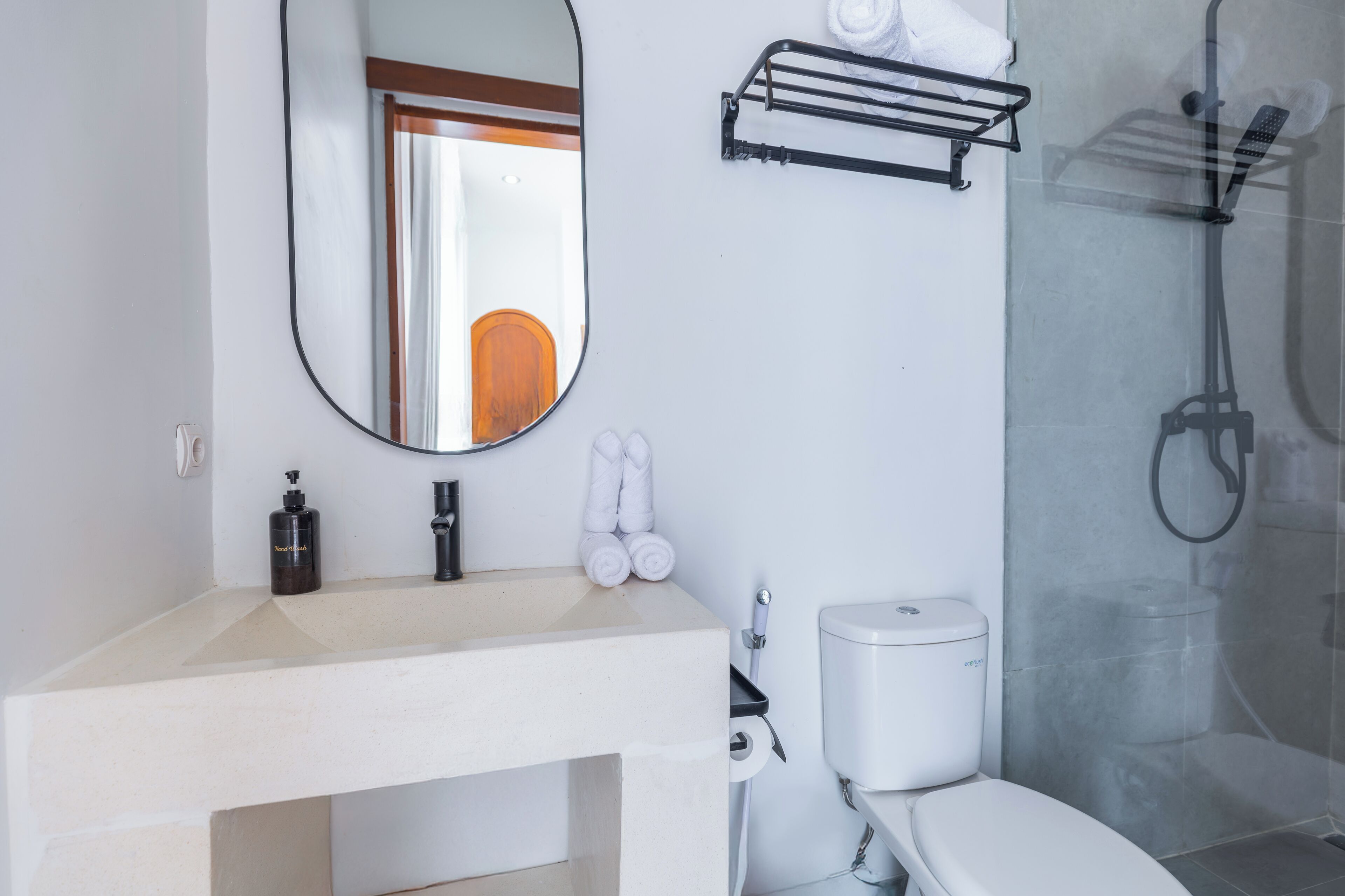Ett badrum med ett vitt handfat, en toalett, en dusch och en spegel.