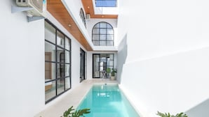 Une piscine intérieure étroite, avec un plafond en bois et de grandes fenêtres.