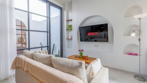 Un salon moderne avec un canapé, un téléviseur fixé au mur et une lampe sur pied.