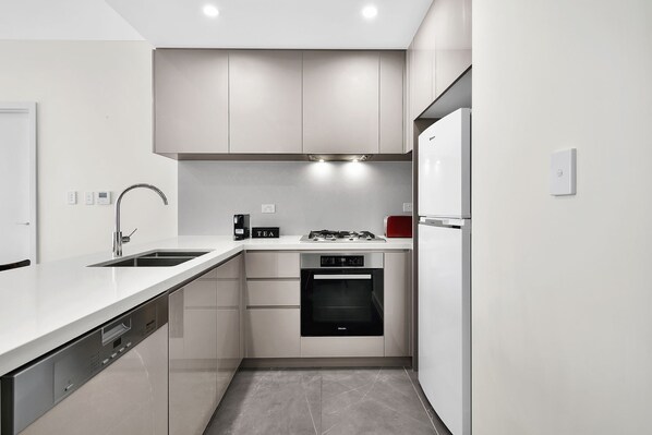 A modern kitchen with a dishwasher, oven, and a coffee maker.