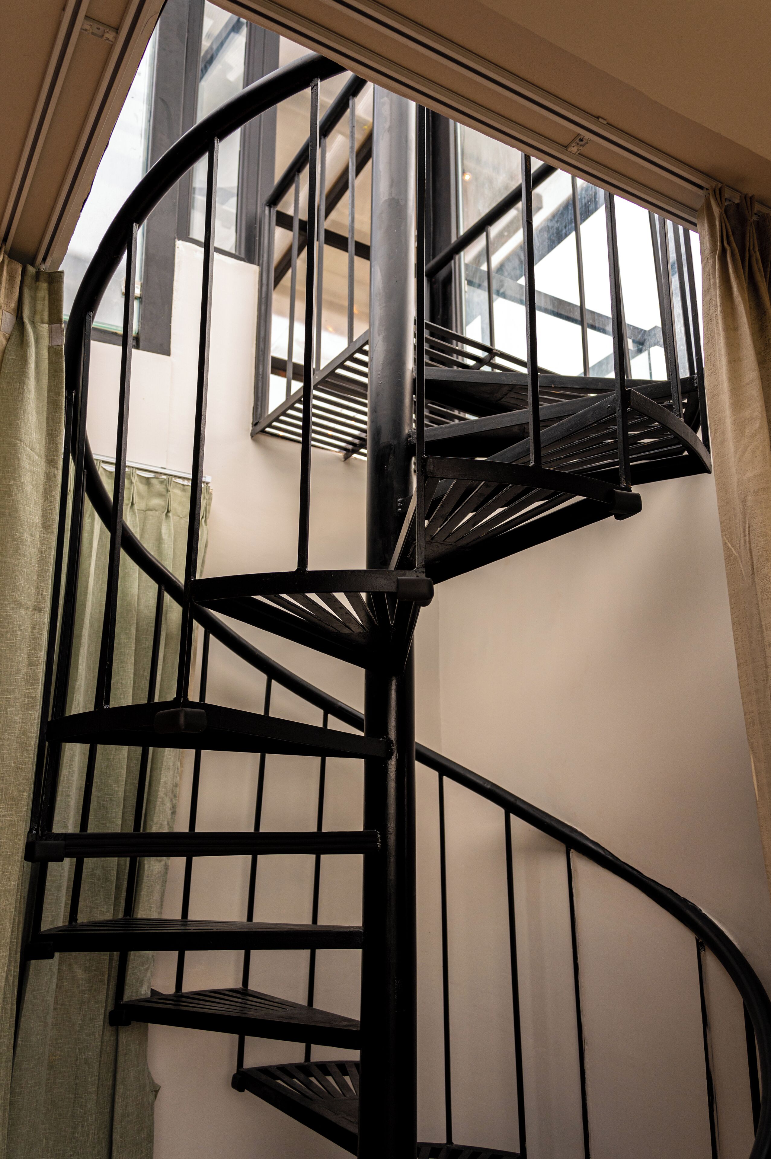 A spiral staircase with a metal railing, leading to an upper floor.