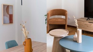 A dining area with a wooden table, a brown vase with dried plants, and a blue table with two white vases. - Central Downtown Living (Athina)