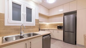 A modern kitchen with stainless steel appliances, a double sink, and light wood cabinetry. - Central Downtown Living (Athina)