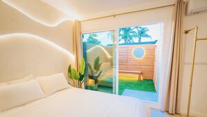 A modern bedroom with a large bed, a sliding glass door to a patio, and a wooden deck.