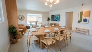 A modern dining area with a round table set for six, surrounded by six wooden chairs.