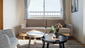 A living room with a sofa, a small round table, and a potted plant. - E-US NAEBO601 (Sapporo)