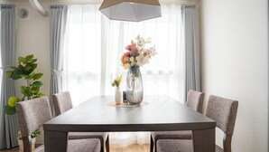 A dining area with a rectangular table, six upholstered chairs, a vase with flowers, and a ceiling light fixture. - E-US NAEBO601 (Sapporo)