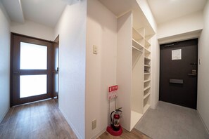 A hallway with a fire extinguisher, a door with a sign, and a staircase. - E-US NAEBO601 (Sapporo)