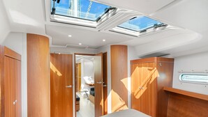 Un interior moderno con armarios de madera, una cama con colchón blanco y tragaluces que dejan entrar luz natural.