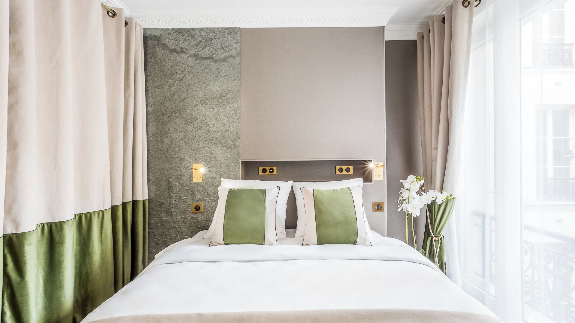 A hotel room with a bed, curtains, a textured wall, and a nightlight.