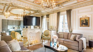 Un salon luxueux avec une cheminée, des meubles élégants et un grand tableau accroché au mur.
