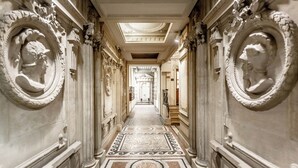 Un vaste hall d’entrée orné de colonnes richement décorées, de sculptures complexes sur les murs et d’un sol à motifs.