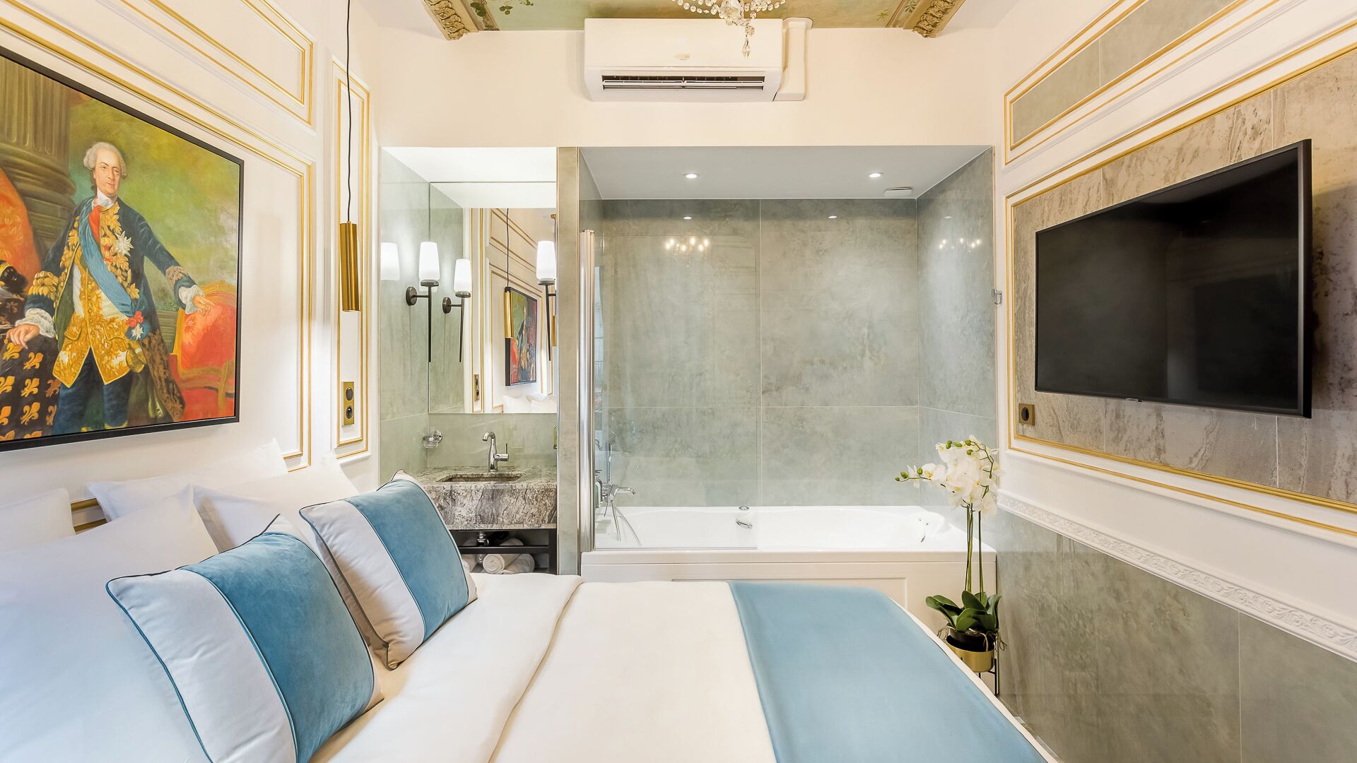 A luxurious bedroom with a large bed, a TV mounted on the wall, and a modern bathroom with a bathtub and shower.