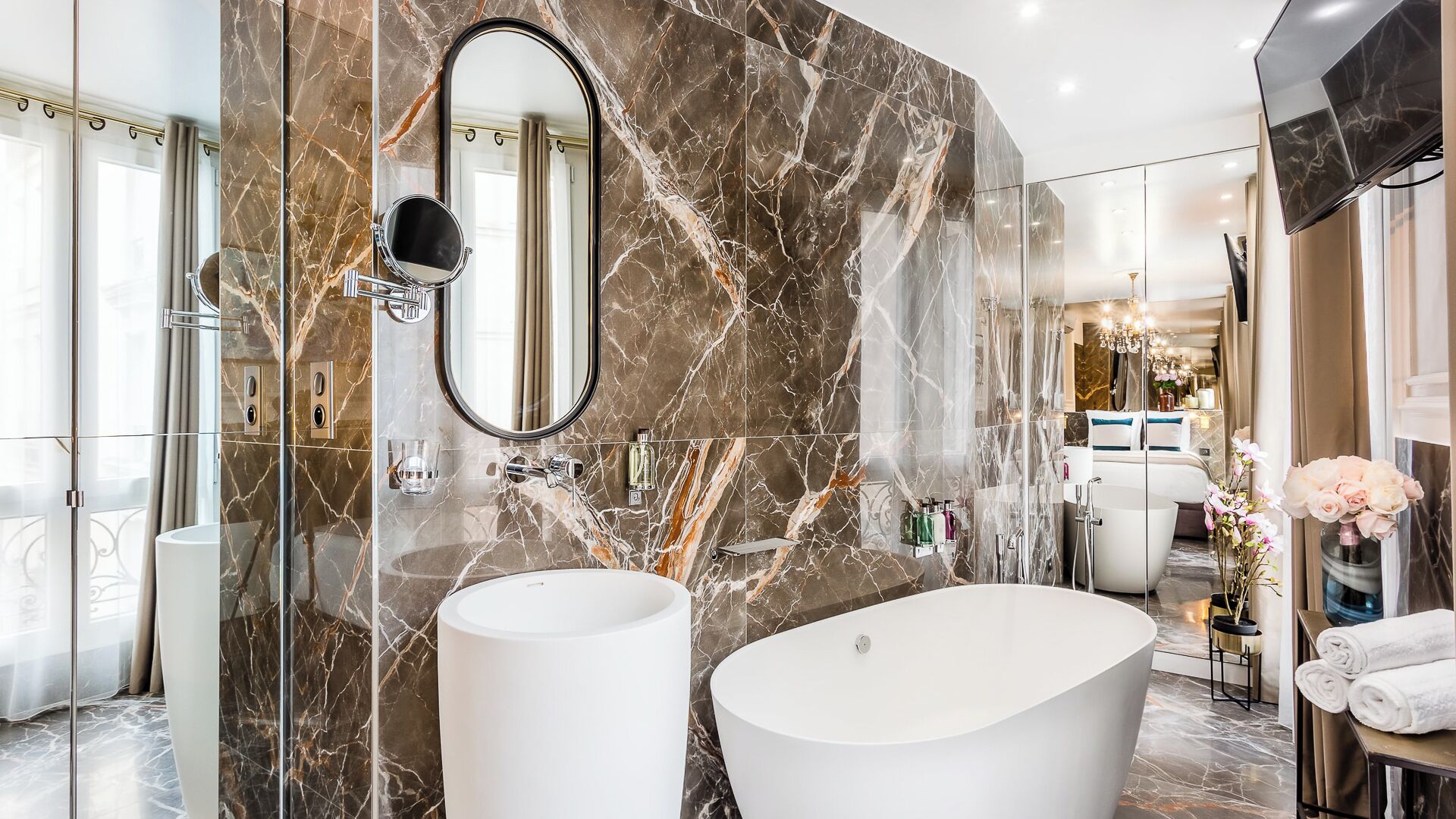 A luxurious bathroom with two large white sinks, a freestanding bathtub, and a large mirror.