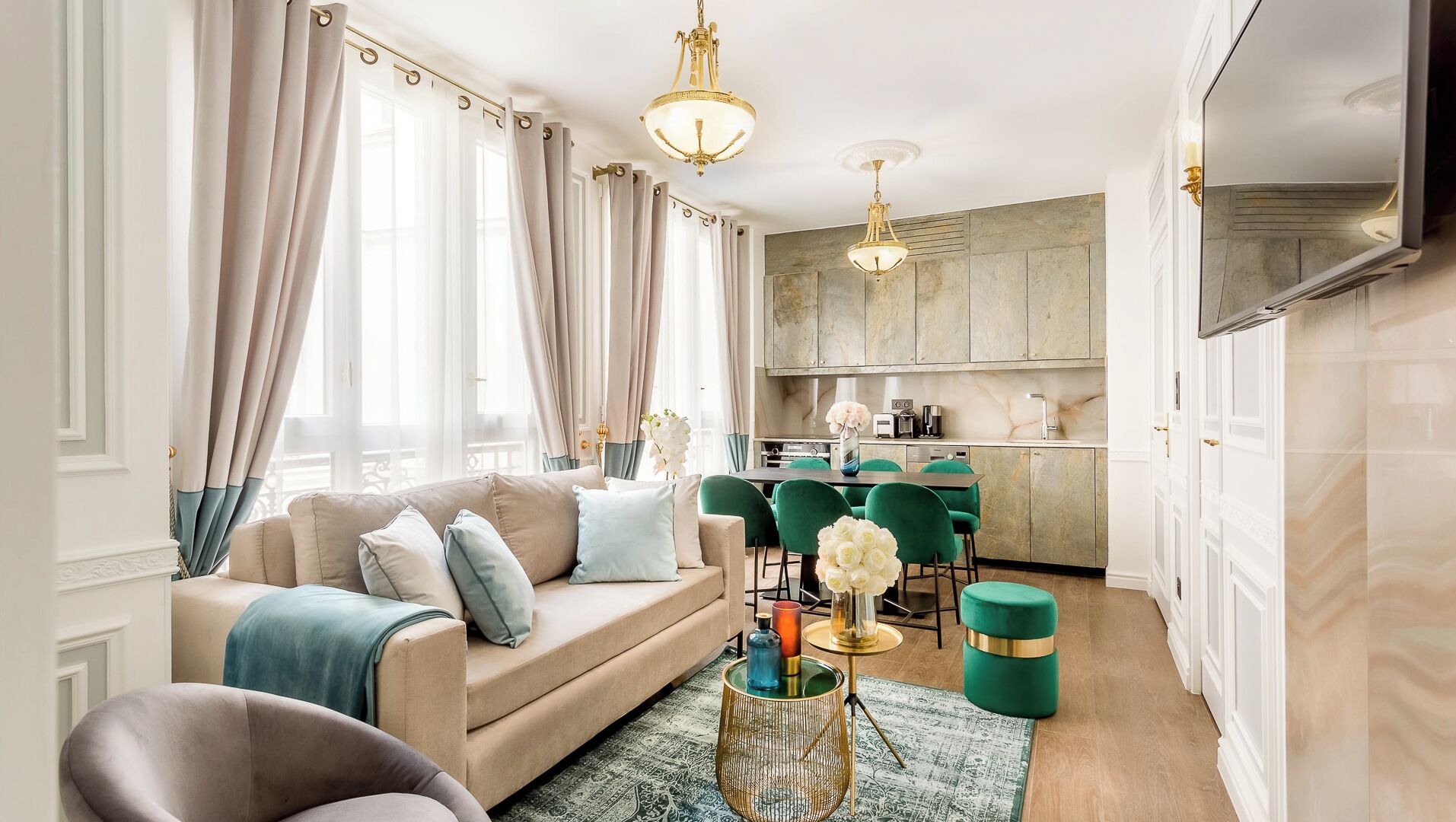 A modern living room with a sofa, green chairs, a coffee table, and a kitchen area with a dining table.