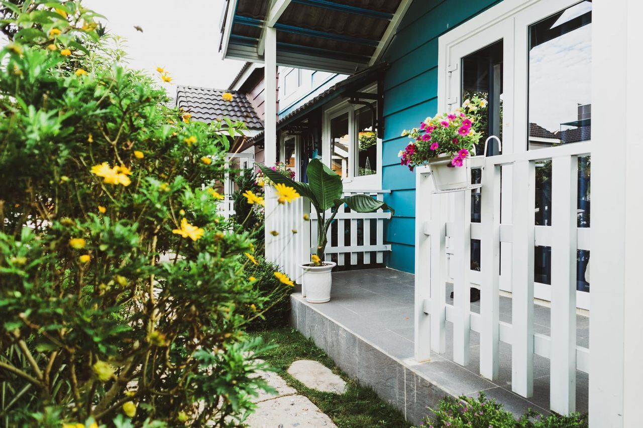 A house with a porch, white picket fence, and potted plants.