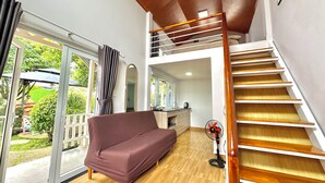 Ein modernes Interieur mit einer Holztreppe, einer Couch und einem Balkon mit Glastüren.