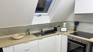 A modern kitchen with white cabinets, a wooden countertop, a built-in oven, and a skylight above the sink. - Stylish Apartment for Families, Technicians, and Business Travelers in Horb (Horb am Neckar)