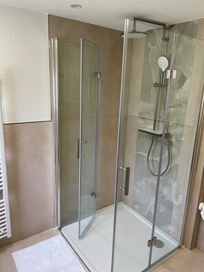 A glass-enclosed shower with a handheld showerhead and a wall-mounted faucet. - Stylish Apartment for Families, Technicians, and Business Travelers in Horb (Horb am Neckar)
