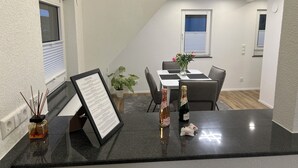 A modern dining area with a black countertop, framed menu, candles, and a bottle of champagne. - Stylish Apartment for Families, Technicians, and Business Travelers in Horb (Horb am Neckar)