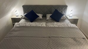 A neatly made bed with a quilted headboard and two bedside tables with lamps. - Stylish Apartment for Families, Technicians, and Business Travelers in Horb (Horb am Neckar)
