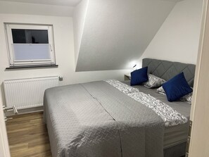A bedroom with a bed, a window, a radiator, and a sloped ceiling. - Stylish Apartment for Families, Technicians, and Business Travelers in Horb (Horb am Neckar)