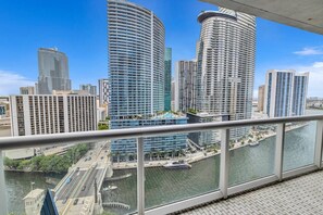 A high-rise hotel with a curved facade, a view of a river, and a bridge in the foreground.