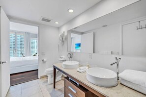 A modern bathroom with two sinks, a large mirror, and a toilet.