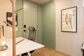 Ein Zimmer mit einem weißen Tisch, einem Stuhl, einer gerahmten anatomischen Illustration an der Wand und einer Tür mit Griff.