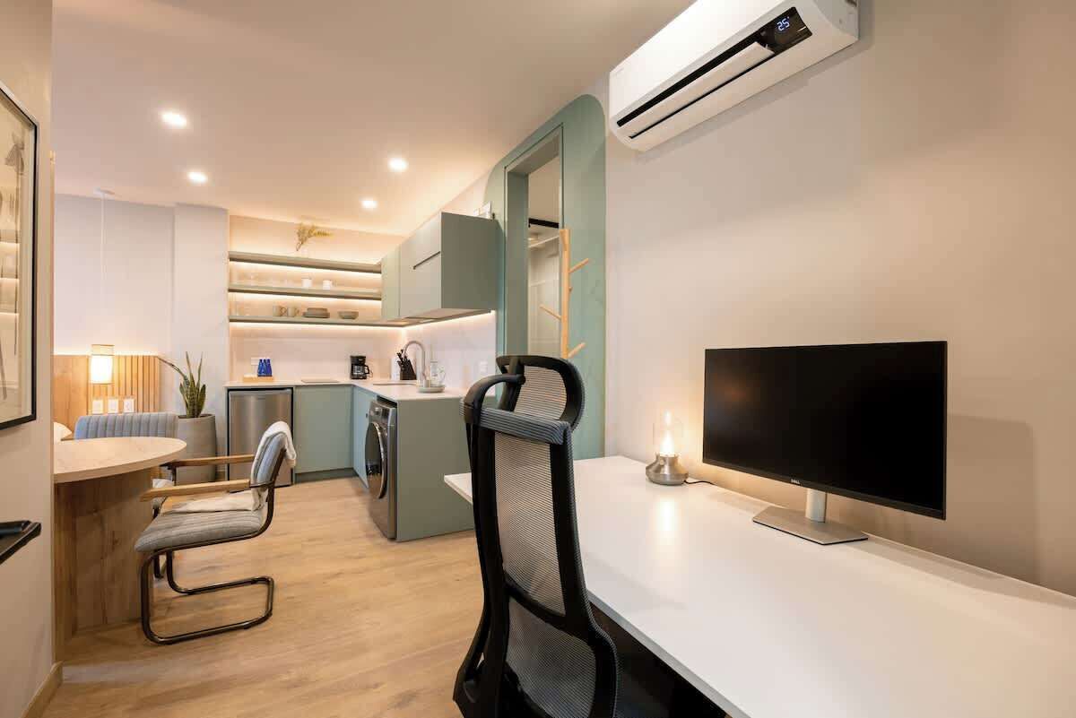 Cuina compacta amb zona de menjador, un televisor i una rentadora.