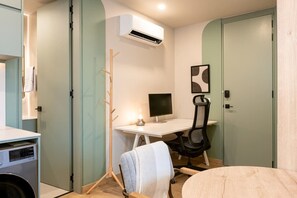Ein kleines Zimmer mit Schreibtisch, Stuhl und Waschmaschine.