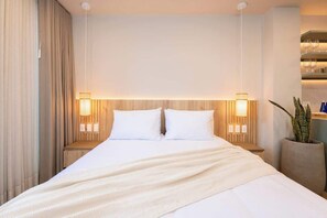 Une chambre d’hôtel avec un grand lit, deux lampes de chevet, une tête de lit en bois et une plante en pot.