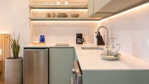 Una cocina moderna con refrigerador empotrado, cafetera y jarra de vidrio sobre la encimera.