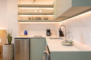 Eine moderne Küche mit einem eingebauten Kühlschrank, einer Kaffeemaschine und einem Glasbehälter auf der Arbeitsfläche.