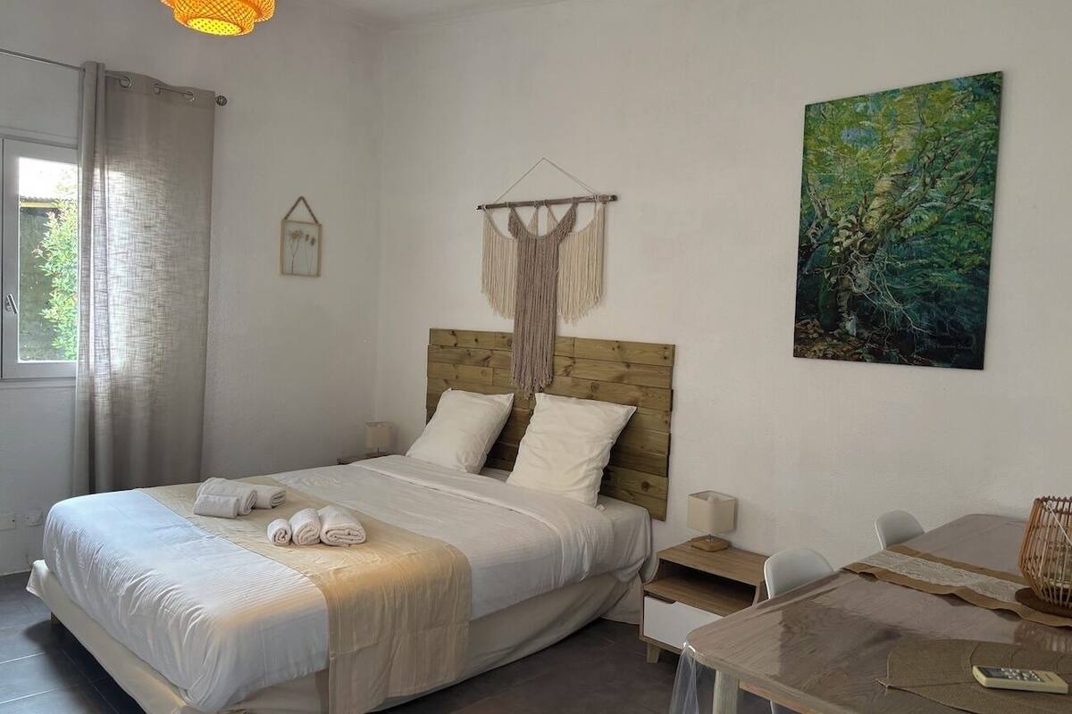A bedroom with a bed, bedside table, and a painting on the wall.