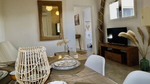 A dining area with a wooden table, chairs, a television, and a mirror on the wall. - GÎTES TERRA DI A BRAVONA (Linguizzetta)