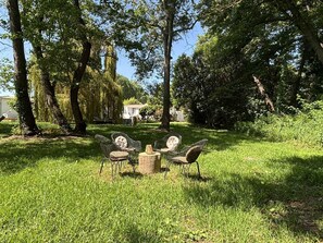 A grassy outdoor area with three wicker chairs and a small wooden table. - GÎTES TERRA DI A BRAVONA (Linguizzetta)