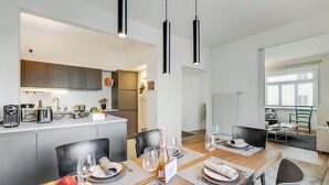 Una cucina moderna con pensili scuri, un'isola centrale e un'area pranzo con tavolo in legno apparecchiato per quattro.