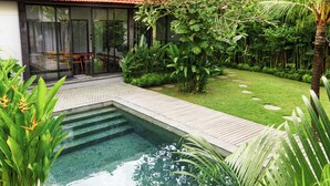 A modern house with a swimming pool, wooden deck, and lush garden.