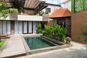 A modern house with a swimming pool, a wooden deck, and a stone statue.