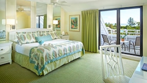 Habitación de hotel con cama, escritorio, silla, balcón y vistas, además de ventilador de techo.