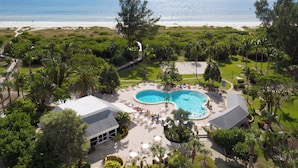Vista aérea de un resort con piscina, acceso a la playa y exuberante vegetación.