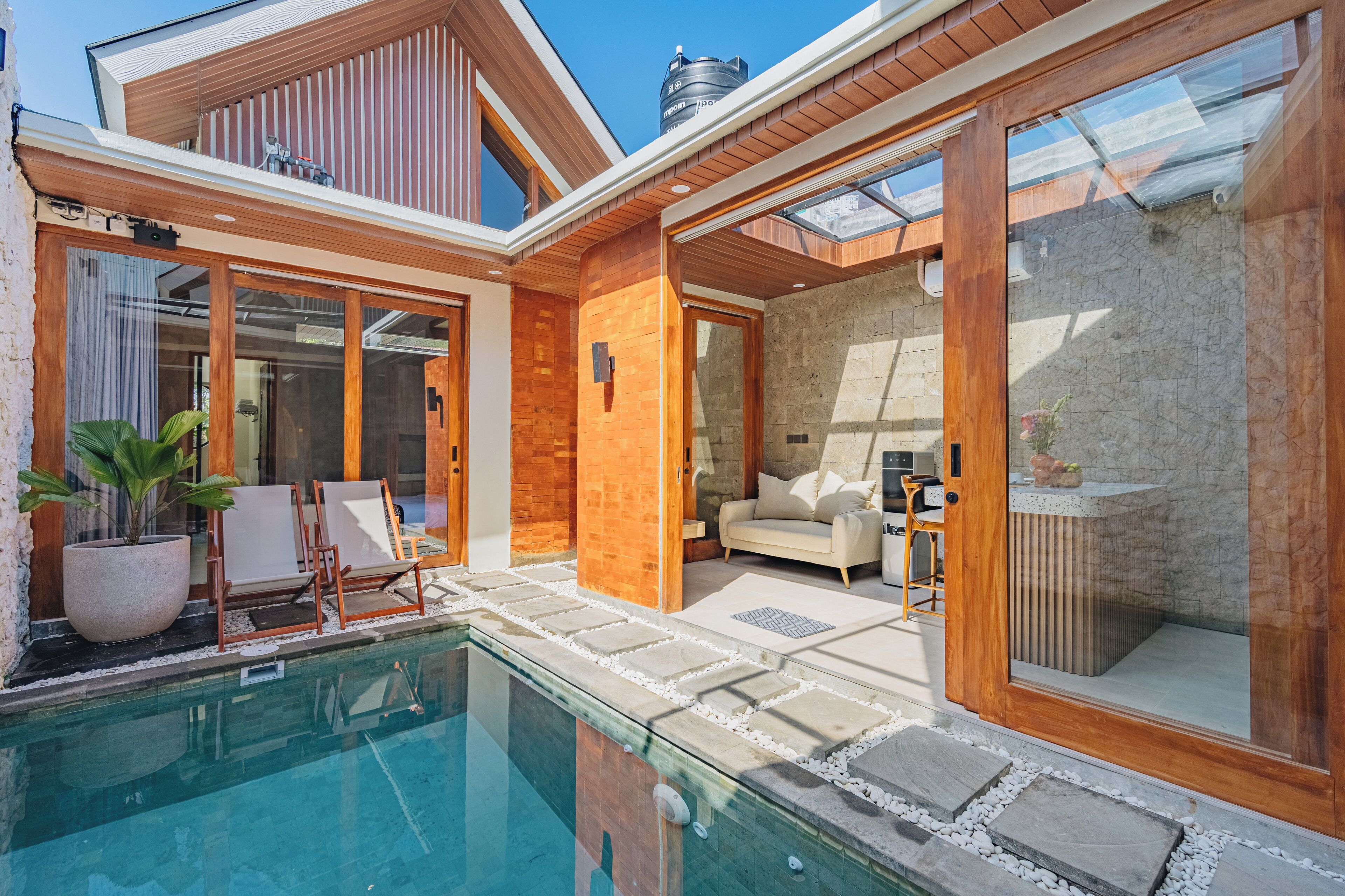 A modern house with a swimming pool, wooden exterior, and a cozy interior with a sofa and chairs.