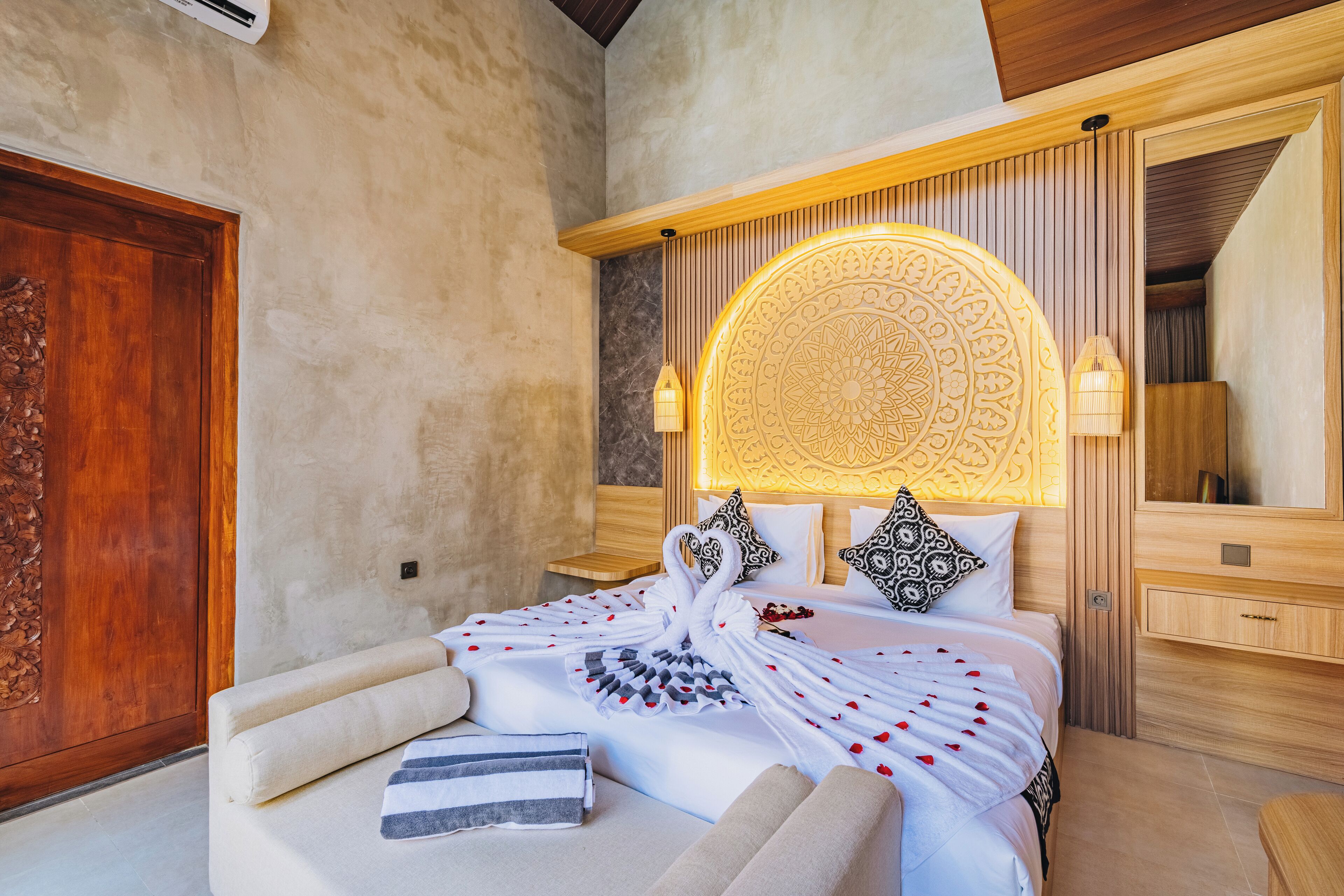 A bedroom with a large bed, a wooden headboard, a mirror, and a wooden wardrobe.