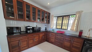 A modern kitchen with wooden cabinets, a microwave, a coffee maker, and a washing machine.