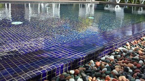 A swimming pool with a tiled edge and a pebble border.