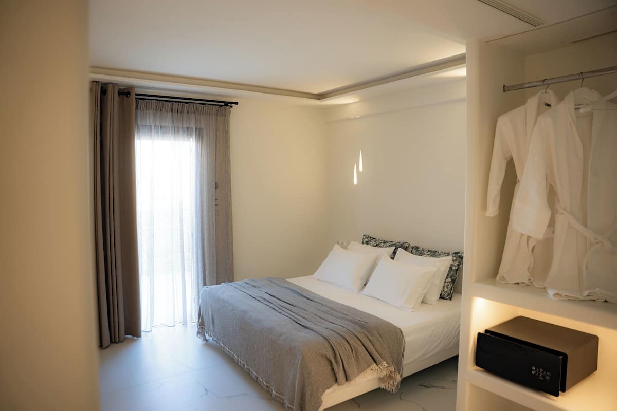 Un dormitorio con cama, armario y ventana con cortinas.
